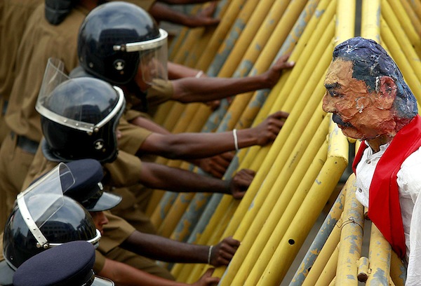 Police take up position behind a metal barrier as students from a group of universities hold a puppet of Sri Lanka's President Rajapaksa over the barrier during a protest in Colombo