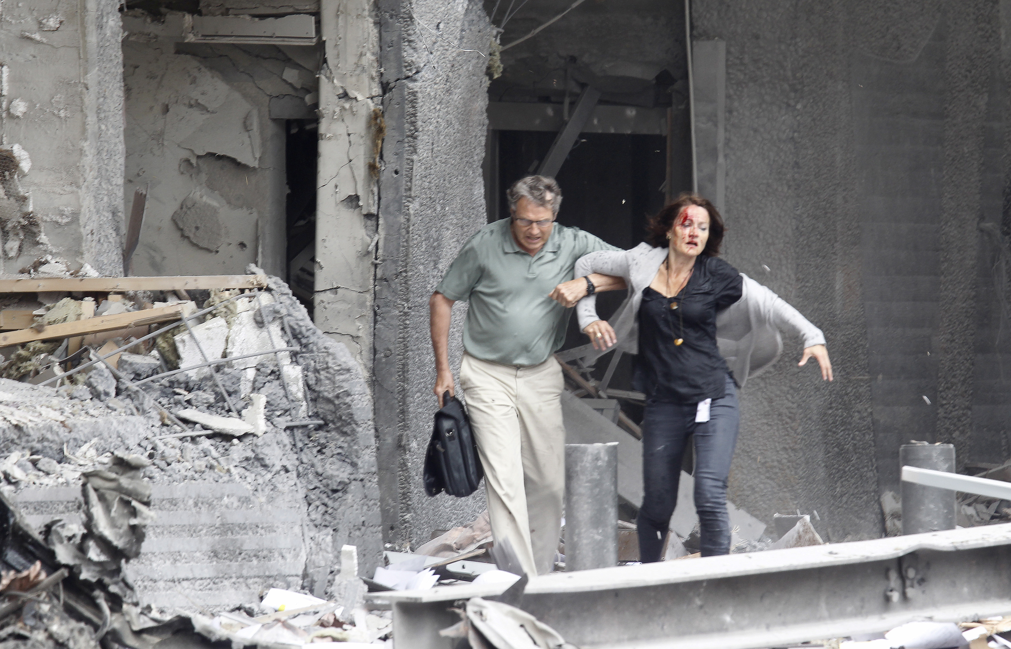 An injured woman is helped by a man at the scene of a powerful explosion that rocked central Oslo July 22, 2011. A huge explosion damaged government buildings in central Oslo on Friday including Prime Minister Jens Stoltenberg's office, injuring several people, a Reuters witness said. The blast blew out most windows on the 17-storey building housing Stoltenberg's office, as well as nearby ministries including the oil ministry, which was on fire. REUTERS/Morten Holm/Scanpix (NORWAY - Tags: CIVIL UNREST IMAGES OF THE DAY) THIS IMAGE HAS BEEN SUPPLIED BY A THIRD PARTY. IT IS DISTRIBUTED, EXACTLY AS RECEIVED BY REUTERS, AS A SERVICE TO CLIENTS. NORWAY OUT. NO COMMERCIAL OR EDITORIAL SALES INNORWAY